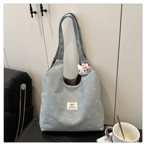 Close-up of light blue canvas tote bag featuring white bow prints and cute character charm