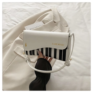Close-up of leather handbag with piano key pattern and golden music embroidery