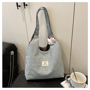 Detail of light blue denim tote with white bow patterns and Hello Kitty plush charm