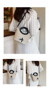 Detail of woven straw bucket bag featuring white lace trim and black bow accent