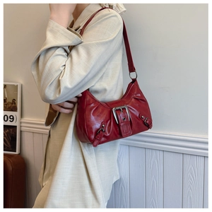 Détail du sac croissant en cuir rouge brillant avec boucle métallique sur la bandoulière