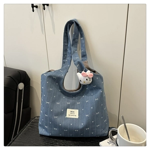 Close-up of blue denim tote bag with white bow patterns and cute plush cat keychain
