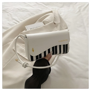Detail of white piano key handbag featuring golden music notes and I LIKE MUSIC text