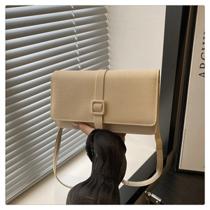 Close-up of beige crossbody bag with fine texture and slim strap in a minimalist setting