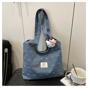 Detail of denim tote bag with heart bow prints and a soft plush kitty charm