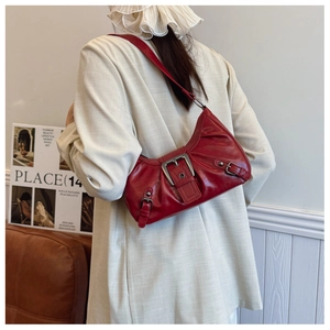 Détail du sac croissant en cuir rouge avec grande boucle métallique et effet plissé