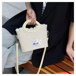 Detail of woven straw bag featuring white lace trim and a blue bow accent label