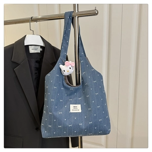 Detail of denim tote bag with white bow patterns and Hello Kitty plush pendant charm