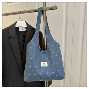 Detail of blue denim tote bag with white bow patterns and soft fabric texture closeup