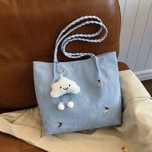 Light blue crossbody tote bag with butterfly ornament and cloud charm on brown chair