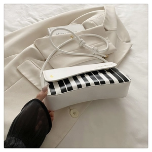 Detail of the piano key pattern and gold I LIKE MUSIC print on a white crossbody bag