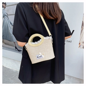 Straw bucket bag with lace trim and bow detail shown on a model in an urban street setting