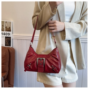 Detail of red glossy underarm bag with silver motorcycle style buckles and zip closure