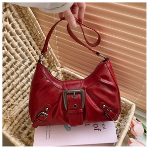 Détail du sac hobo rouge vintage avec boucle en métal dans une ambiance de maison