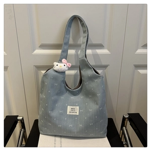 Detail view of denim tote bag with bow patterns and cute plush cat character charm