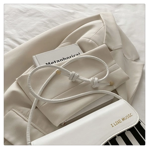 Detail of white piano key handbag with I LIKE MUSIC text and elegant knotted strap