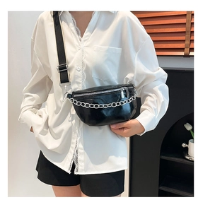 Detail view of black glossy waist bag featuring silver chain and adjustable contrast strap