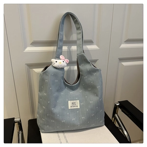 Detail of light blue denim tote bag with white bow prints and cute kitty plush charm