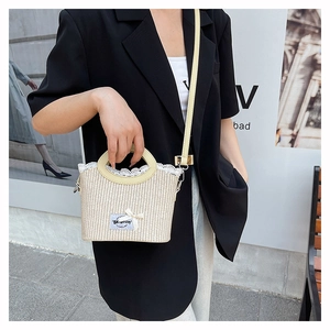 Detail of woven straw bag with delicate lace trim, bow decor, and leather strap