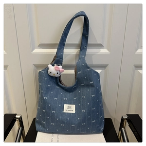 Detail of blue denim tote bag with white heart patterns and plush charm on a chair