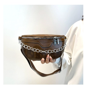 Detail of brown leather fanny pack with chunky silver chain and wide canvas strap