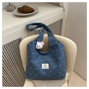 Blue denim tote bag with bow print, white label detail and plush cat keychain charm
