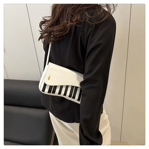 Detail view of piano key handbag with gold treble clef clasp and black white stripes