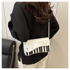 Detail view of piano key crossbody bag with I LIKE MUSIC print shown on a model