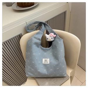 Detail of light blue canvas tote bag with bow prints and cute kitty plush charm