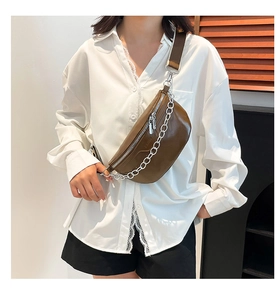 Detail of dark brown leather saddle bag with silver metal chain and adjustable strap