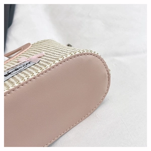 Detail van strooien emmer tas met roze leren bodem en BkoBoom strik decoratie