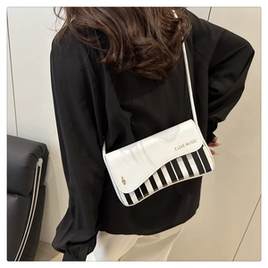 Detailed view of music-themed crossbody bag with piano key design and golden logo
