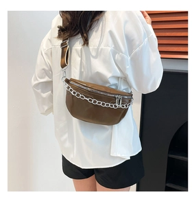 Detail view of glossy brown waist bag featuring silver metal chain and adjustable strap