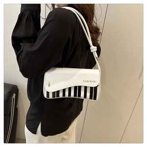 Detail of music-themed handbag featuring piano key pattern and gold musical note print