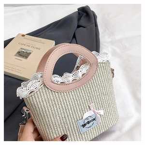 Detail van strooien handtas met witte kantafwerking en roze leren handvaten