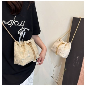 Detail of floral embroidery and pearl drawstring on beige straw bucket bag