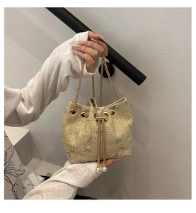 Detail of beige woven bucket bag featuring floral embroidery and luxury pearl drawstrings