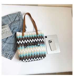 Close-up of woven straw tote bag featuring colorful wave patterns and Summer applique
