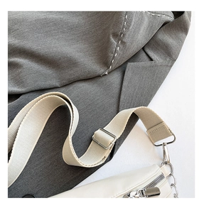 Detail of minimalist beige crossbody bag with silver hardware and canvas strap