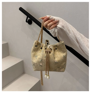 Detail of straw bucket bag featuring pink flower embroidery and pearl chain strap