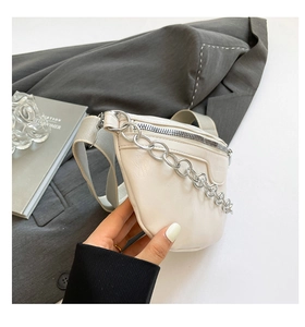 Detail of cream waist bag with silver chain and wide canvas strap on gray suit