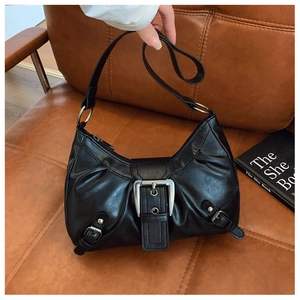 Détail d'un sac à bandoulière noir plissé avec boucle argentée sur canapé vintage en cuir