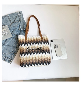 Overhead view of a woven straw tote bag with Summer embroidery and daily essentials