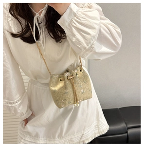 Detail of straw bucket bag with floral embroidery, pearl charms and gold chain strap