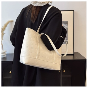 Detail of cute puppy embossed pattern on off-white leather tote bag with shoulder strap