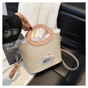 Detail van beige strooien tas met roze leren handvatten, kant en een strik decoratie