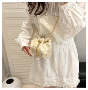 Detail of floral embroidery and pearl drawstring on a beige woven bucket bag