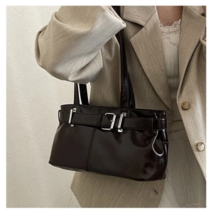 Detailed close-up of dark glossy faux leather tote bag with stylish silver metal buckle