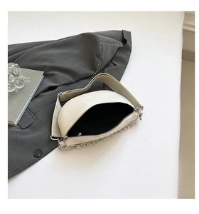 Top view of cream white half-moon crossbody bag with silver chain and wide fabric strap
