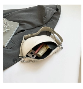 Internal storage of the beige half-moon waist bag showing phone and cosmetics